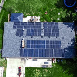 An alternative perspective of a house roof adorned with solar panels, featuring a SolarUp technician actively involved in the installation procedure.
